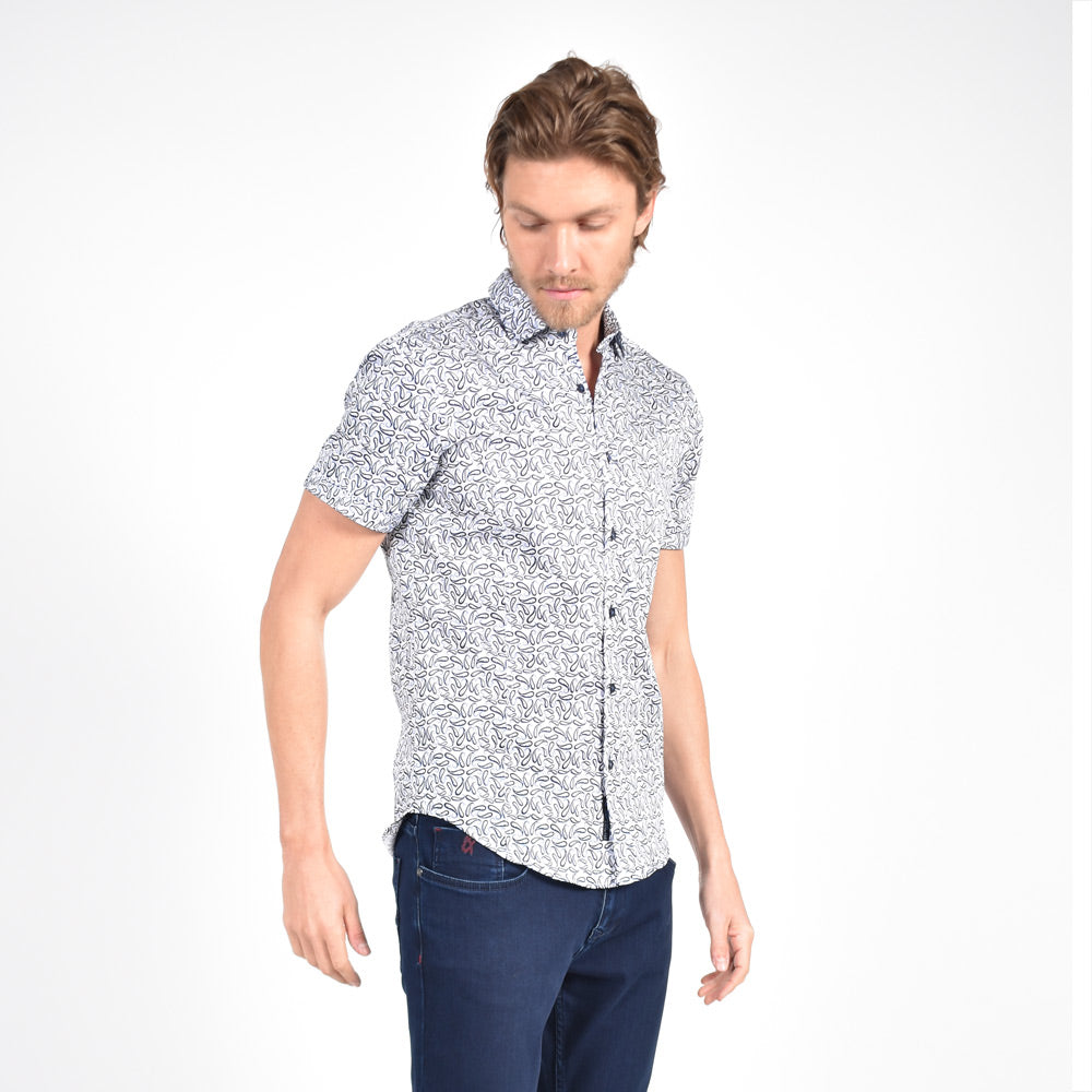 Model in short-sleeve white button-up in blue and navy paisley print.