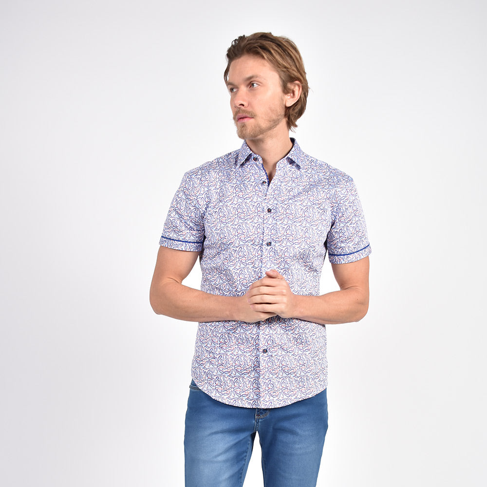 Model in short-sleeve white button-up in blue and red paisley print, with blue polka dot trim.