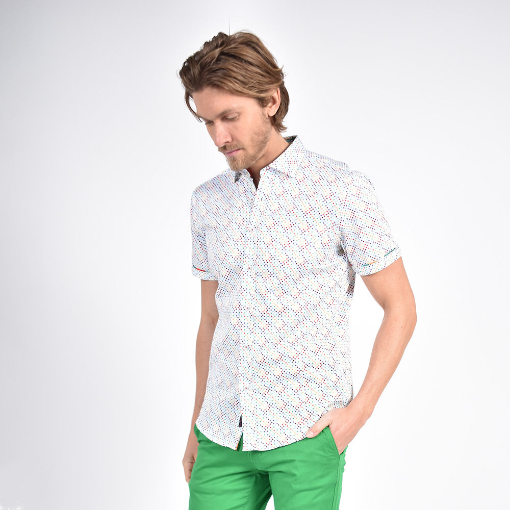 Model in white, short-sleeve button up with multi-color small polka dot print.