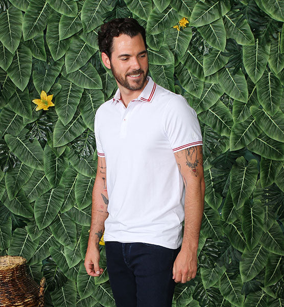 White polo with tipped collar; two-button, red-trimmed placket; and striped, ribbed armbands.
