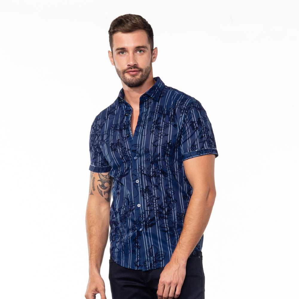 Model in short-sleeve navy blue button up with white stripes and black floral flocking.