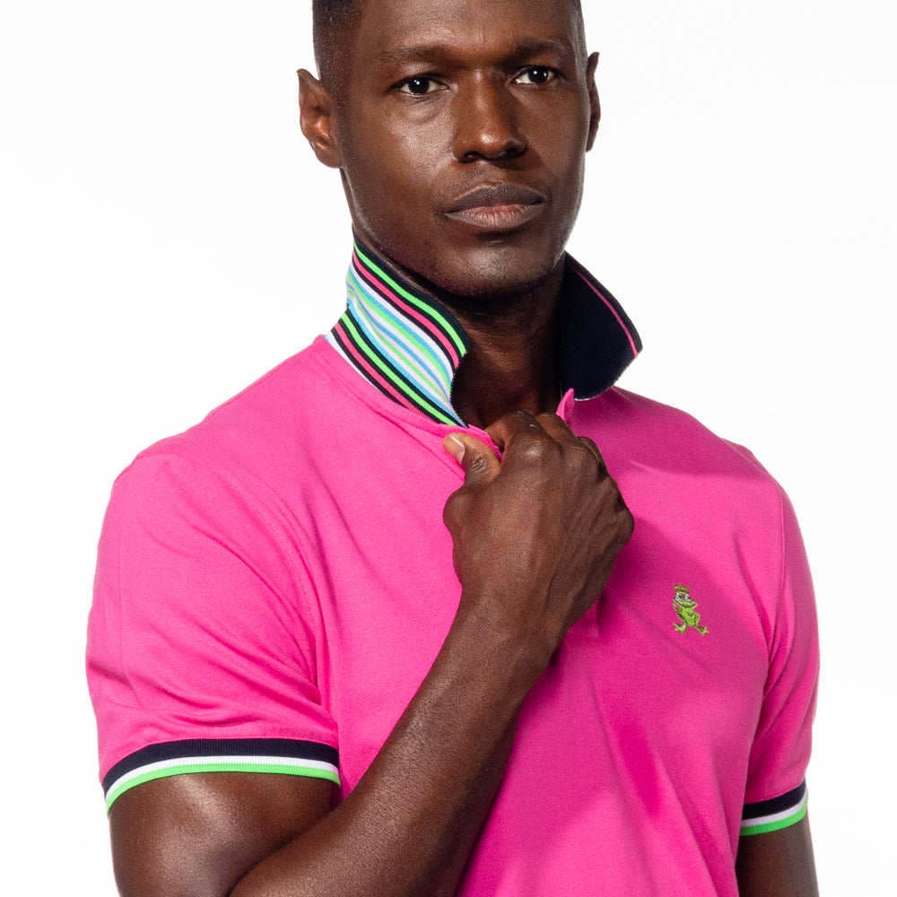 Model wearing fuchsia polo with flipped, striped collar. 