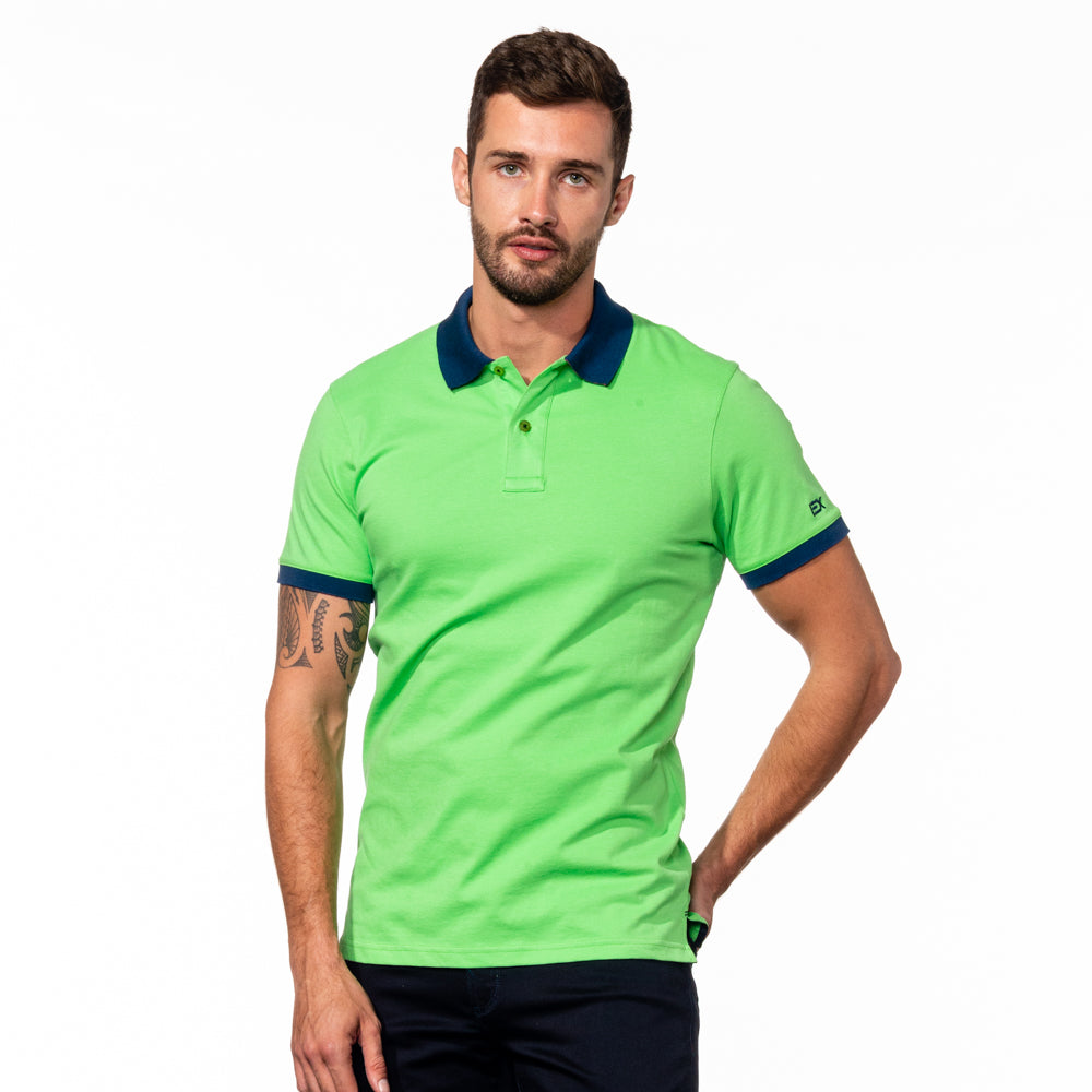 Model in bright-green polo with navy-blue collar and ribbed armbands.