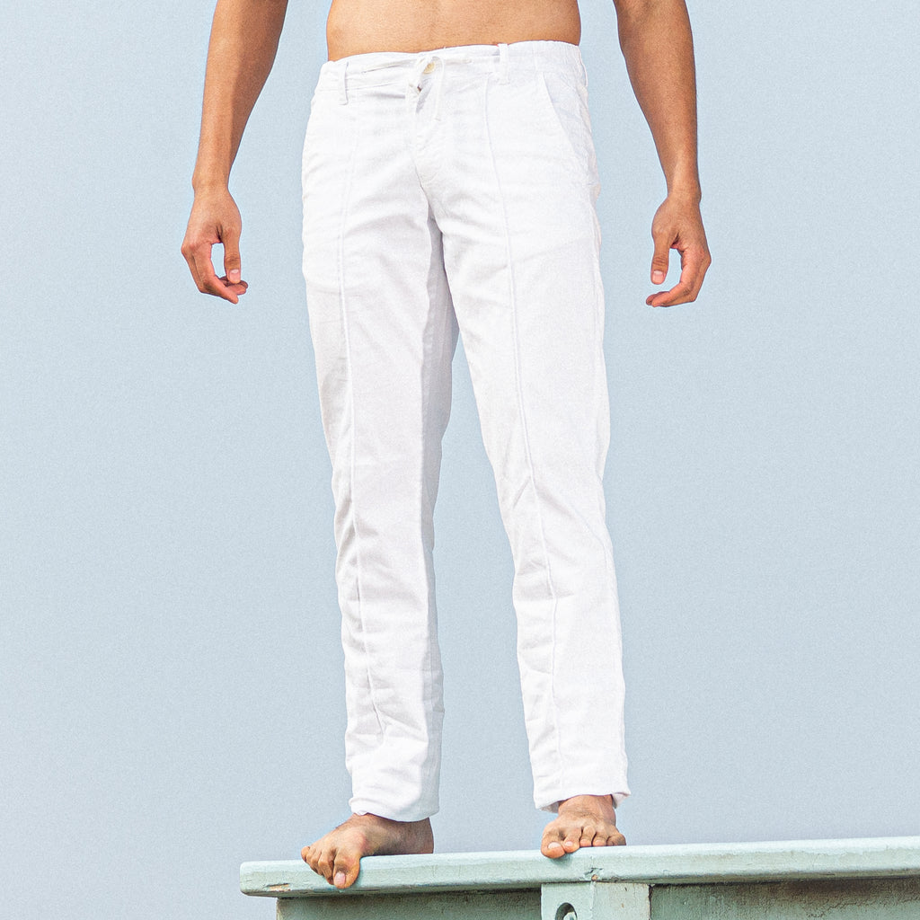 model wearing white slim fit chino pants standing on beach