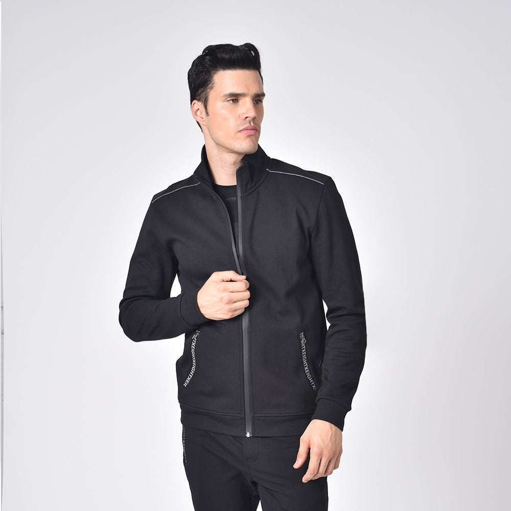 Model in black, cotton track jacket with hidden, full front-zipper; grey piping; and logo-lined side zip-pockets.