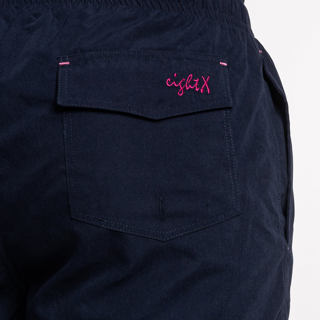 Back of navy swim shorts showing back pocket and a magenta Eight X logo on the pocket flap