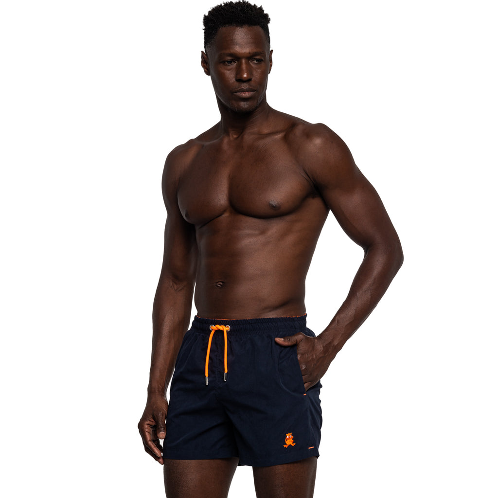 Model wearing navy swim shorts with orange drawstrings and frog logo