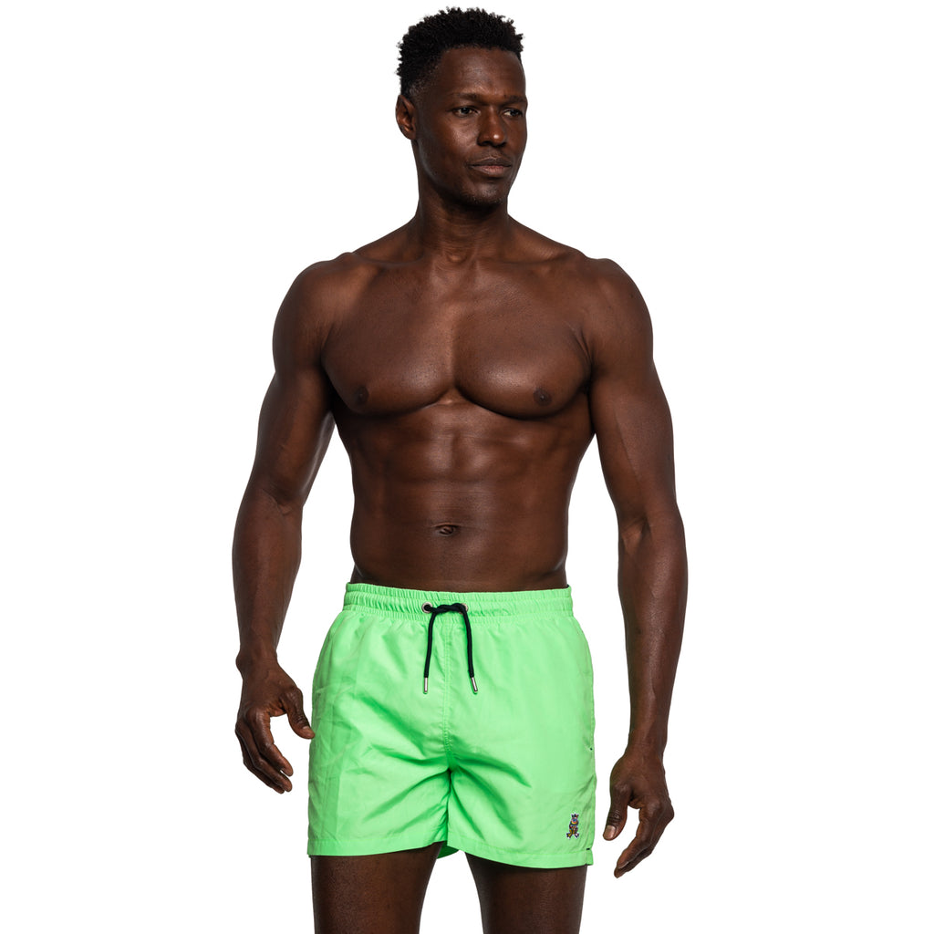 Model wearing green swim shorts with black drawstrings and frog logo