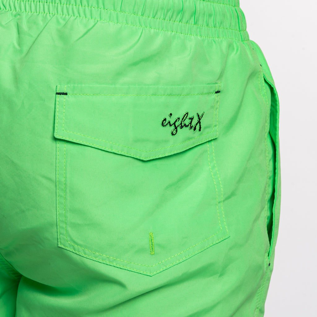 Back of green swim shorts showing back pocket and a black Eight X logo on the pocket flap