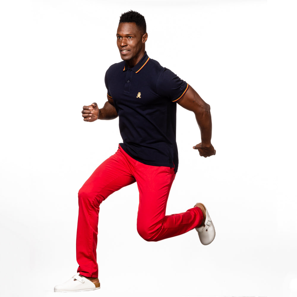 Model in navy polo with tipped collar, two-button placket, and striped, ribbed armbands. Featuring embroidered gold frog mascot.