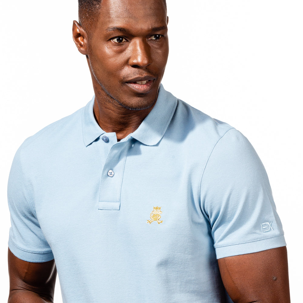 Model in light-blue polo with two-button placket, ribbed armbands, embroidered gold frog mascot, and embroidered EX logo on left sleeve. 