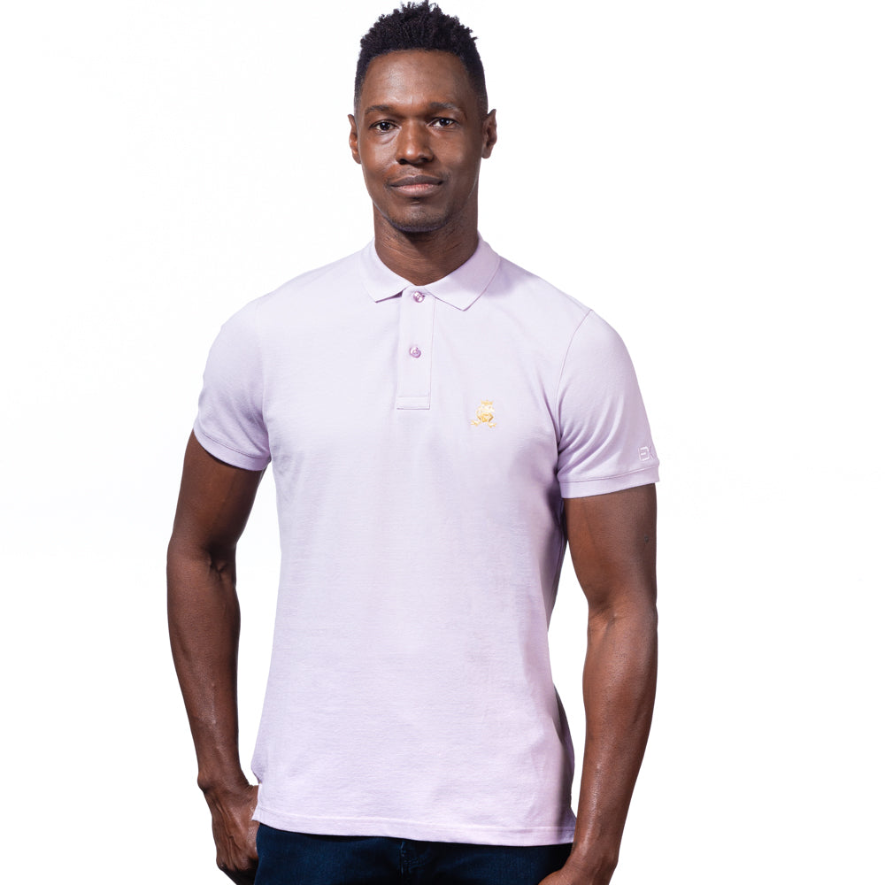 Model in lilac polo with two-button placket, ribbed armbands, and embroidered gold frog mascot. 
